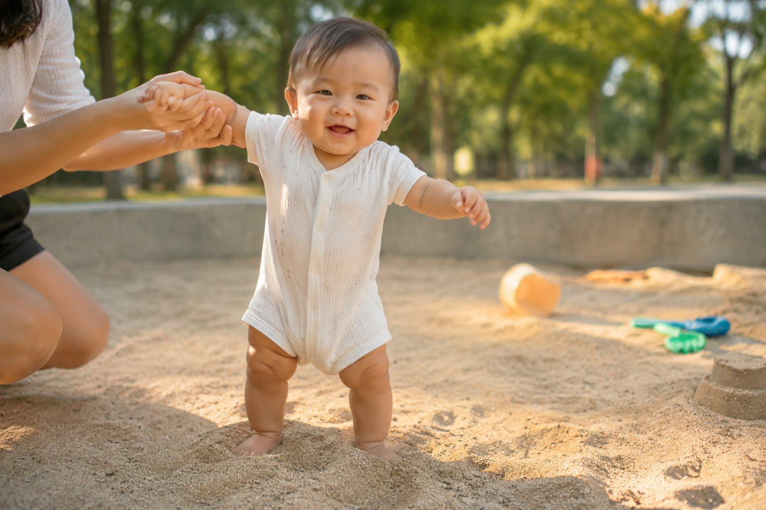 A chubby 12-month-old Chinese toddler barefoot standing unsteadily but happily in a clean sandpit, warm afternoon sunlight, soft shadows, tiny toes gripping the loose sand, joyful expression, parents hands slightly visible supporting from the side, outdoor natural environment, macro details on the feet and sand texture, photorealistic, 8k, ultra-clear --ar 3:4