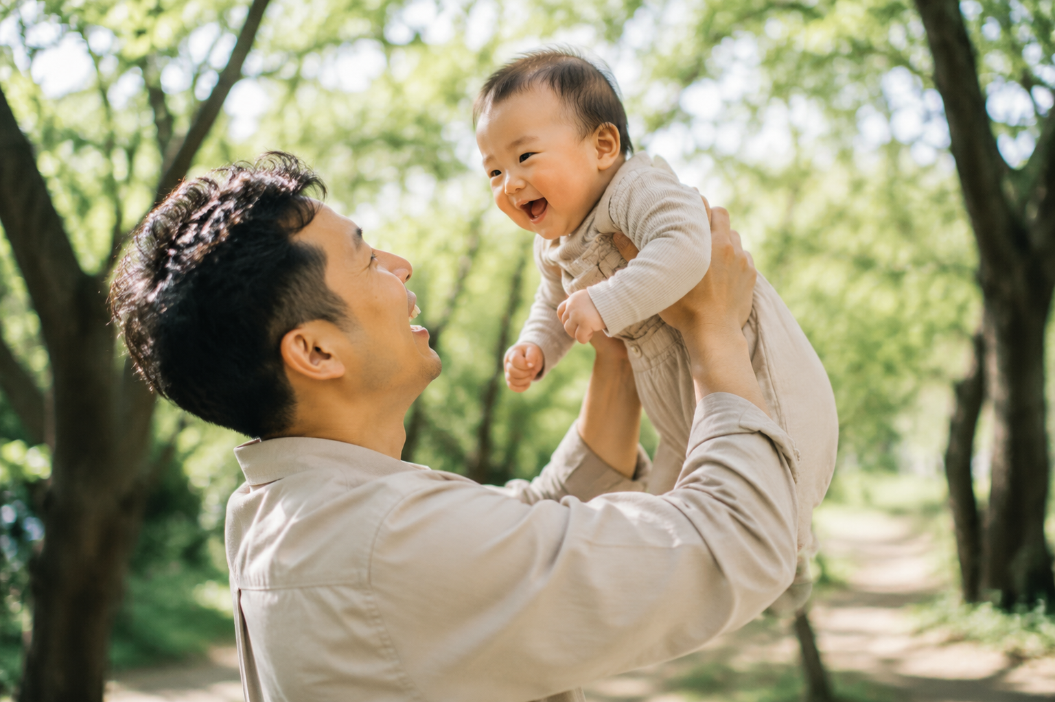 A professional lifestyle photo of a handsome Chinese dad gently lifting his laughing baby up to his eye level. They are standing outdoors under beautiful spring trees with dappled sunlight filtering through the leaves. The dad's hands are securely supporting the baby's underarms and chest. Joyful expressions, crisp focus on faces, blurred nature background, soft cinematic lighting, Kodak Portra 400 film style, photorealistic. --ar 3:4 --style raw --v 6.0