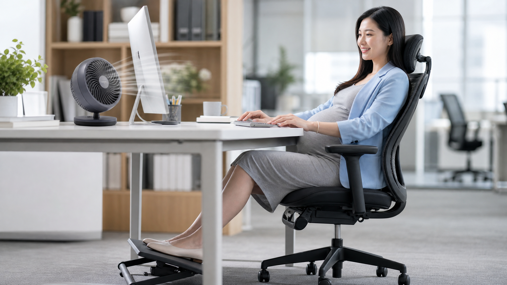 A professional lifestyle photo of a modern Chinese pregnant woman working comfortably at a clean office desk. A stylish, quiet desktop fan (diameter around 18cm) is blowing gently towards her. Her feet are resting on an ergonomic adjustable footrest under the desk. She is smiling and looks refreshed. Bright office lighting, neat environment, shallow depth of field, highly detailed, 8k.