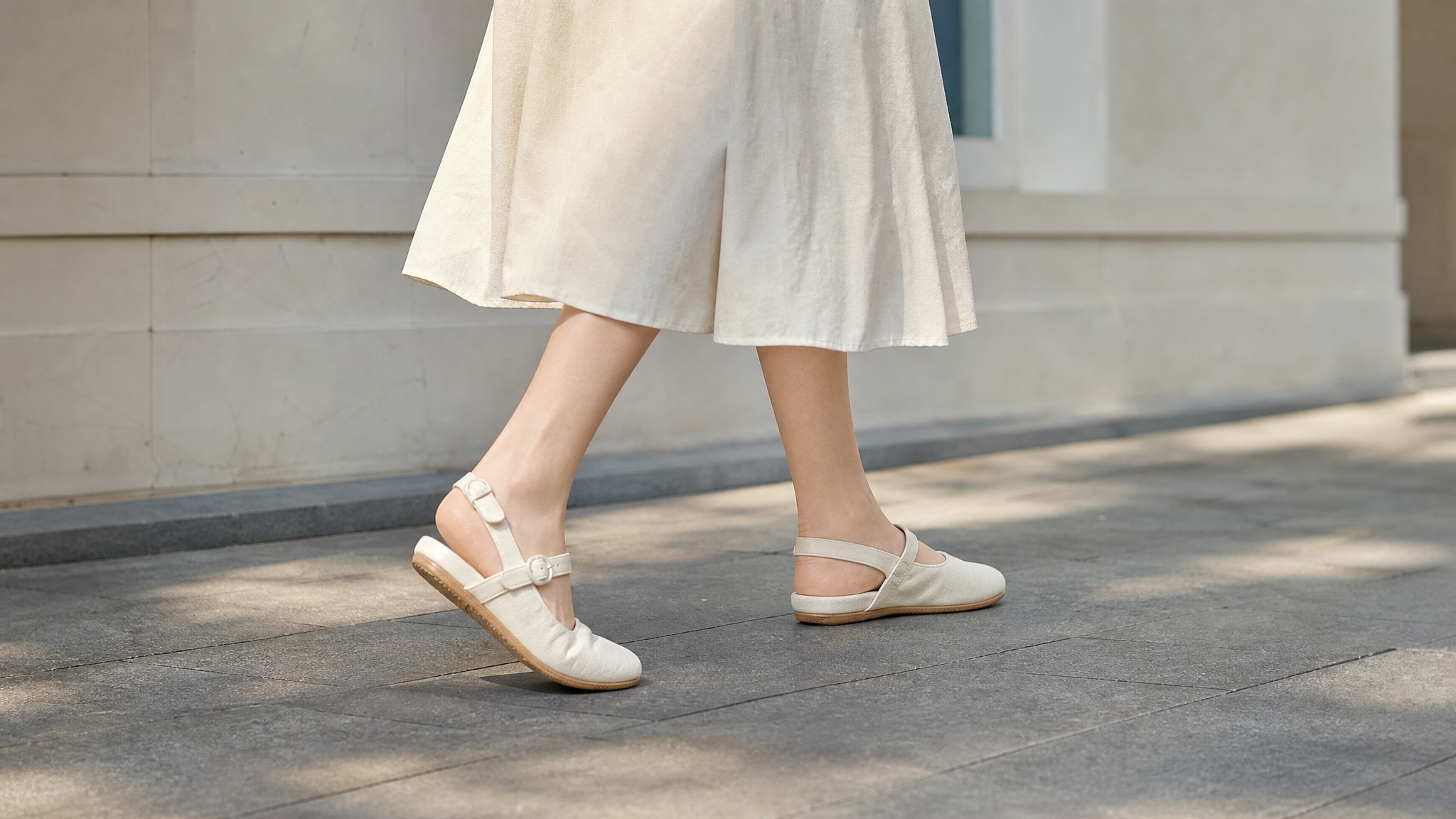 Close-up shot of a Chinese pregnant woman's legs and feet walking on a clean summer street. She is wearing stylish and comfortable soft-soled Mary Jane shoes with back straps, paired with a light-colored elegant midi skirt. The image focuses on the elegant ankle lines and the comfortable fit of the shoes. Bright natural lighting, clean background, aesthetic lifestyle photography, highly detailed, 8k.