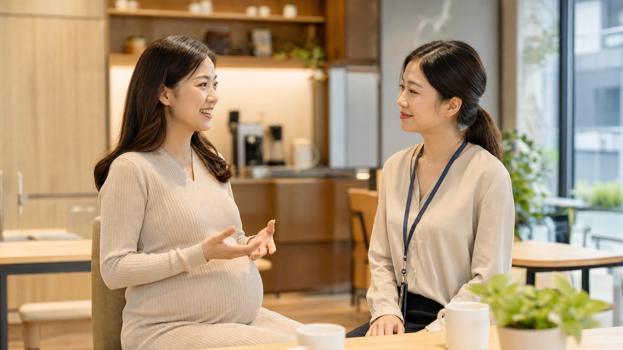 一位面带微笑的中国孕妇正在和一位中国女同事在办公室茶水间友善交谈，孕妇手势温柔，同事表情理解并点头，温馨的职场氛围，日剧暖色调，高质量摄影，光线柔和，人物面部清晰，8k分辨率。