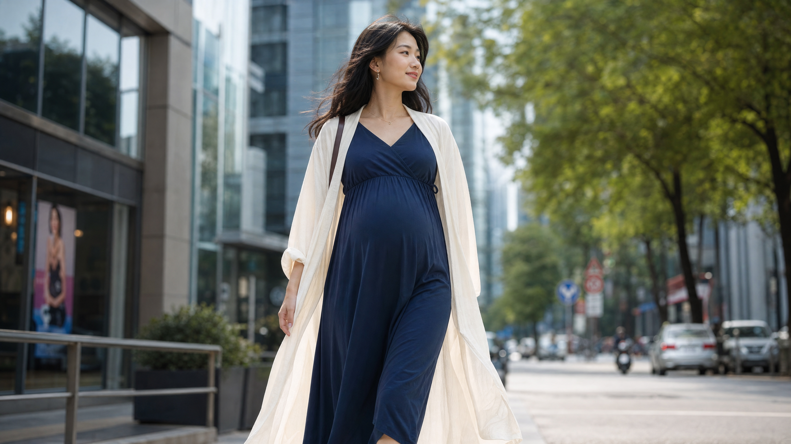 A beautiful Chinese pregnant woman walking confidently on a modern city street in early summer. She is wearing a cream-white light sun-protection shawl over a high-waisted (empire waist) navy blue A-line midi dress. Gentle sunlight, cinematic street photography, elegant and comfortable style, high fashion editorial, 8k resolution, photorealistic.