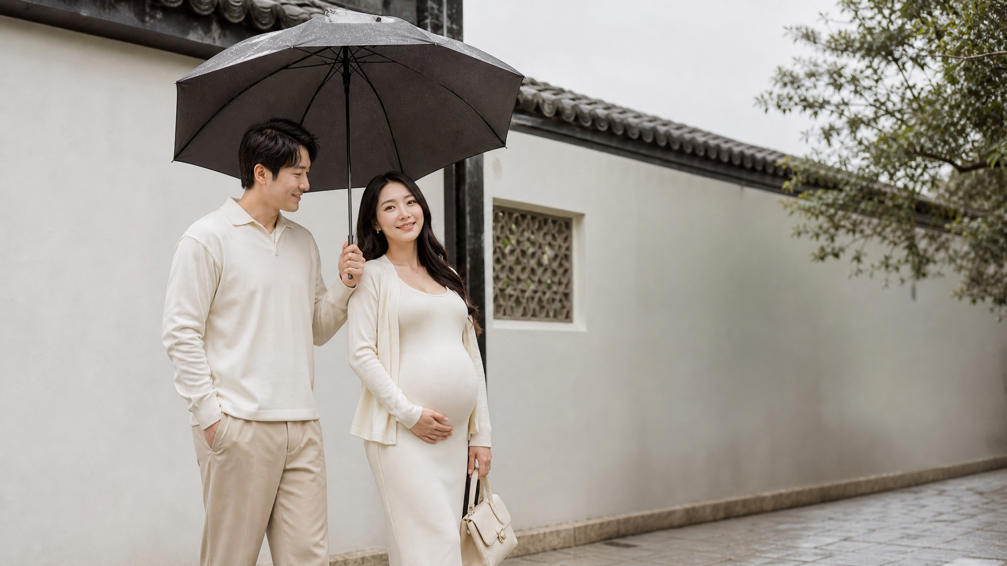 A caring Chinese husband holding a large umbrella for his beautiful pregnant wife in a light-colored outfit. They are standing in front of a light-colored wall with a small roof overhang. The wife is posing naturally for an OOTD shot, looking fresh and happy despite the cloudy weather, soft diffused lighting, romantic and lifestyle photography, 8k. --ar 3:4