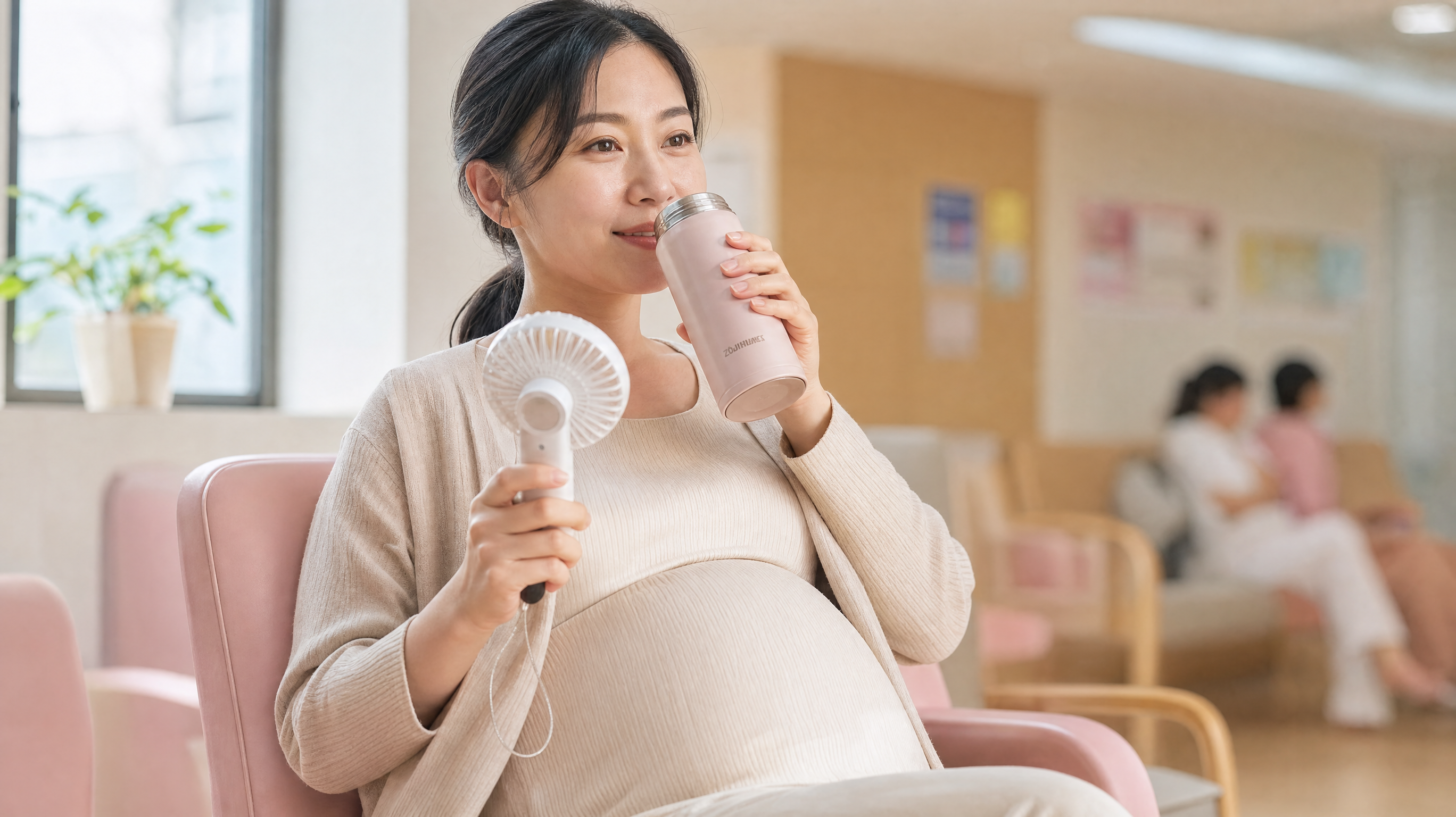 A close-up of a smiling Chinese pregnant woman sitting comfortably in a bright waiting area, holding a small portable fan and drinking warm water from a thermos. Soft pastel colors, warm and reassuring atmosphere, high quality, 8k resolution, photorealistic --ar 16:9